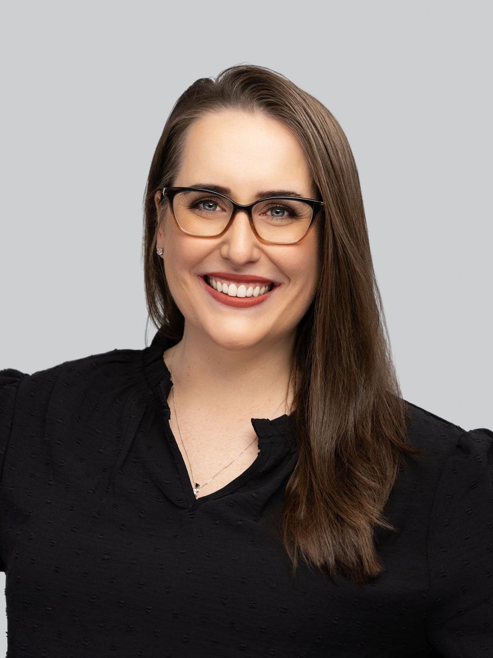 A woman wearing glasses and a black shirt is smiling.