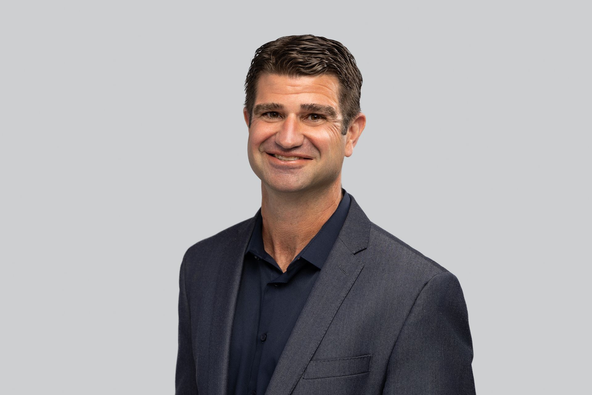 A man in a suit and blue shirt is smiling for the camera.