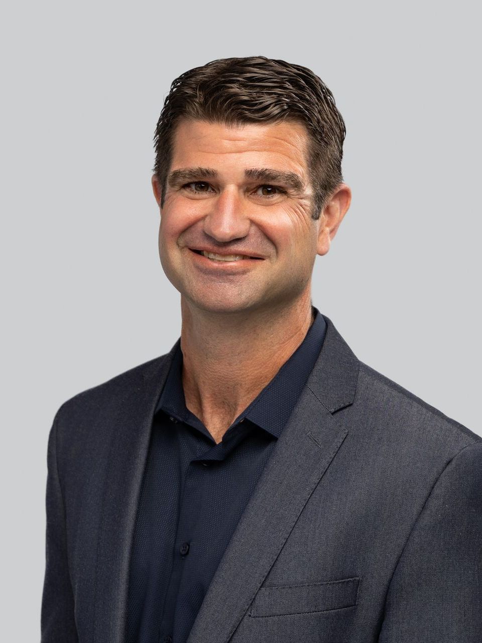 A man in a suit and blue shirt is smiling for the camera.