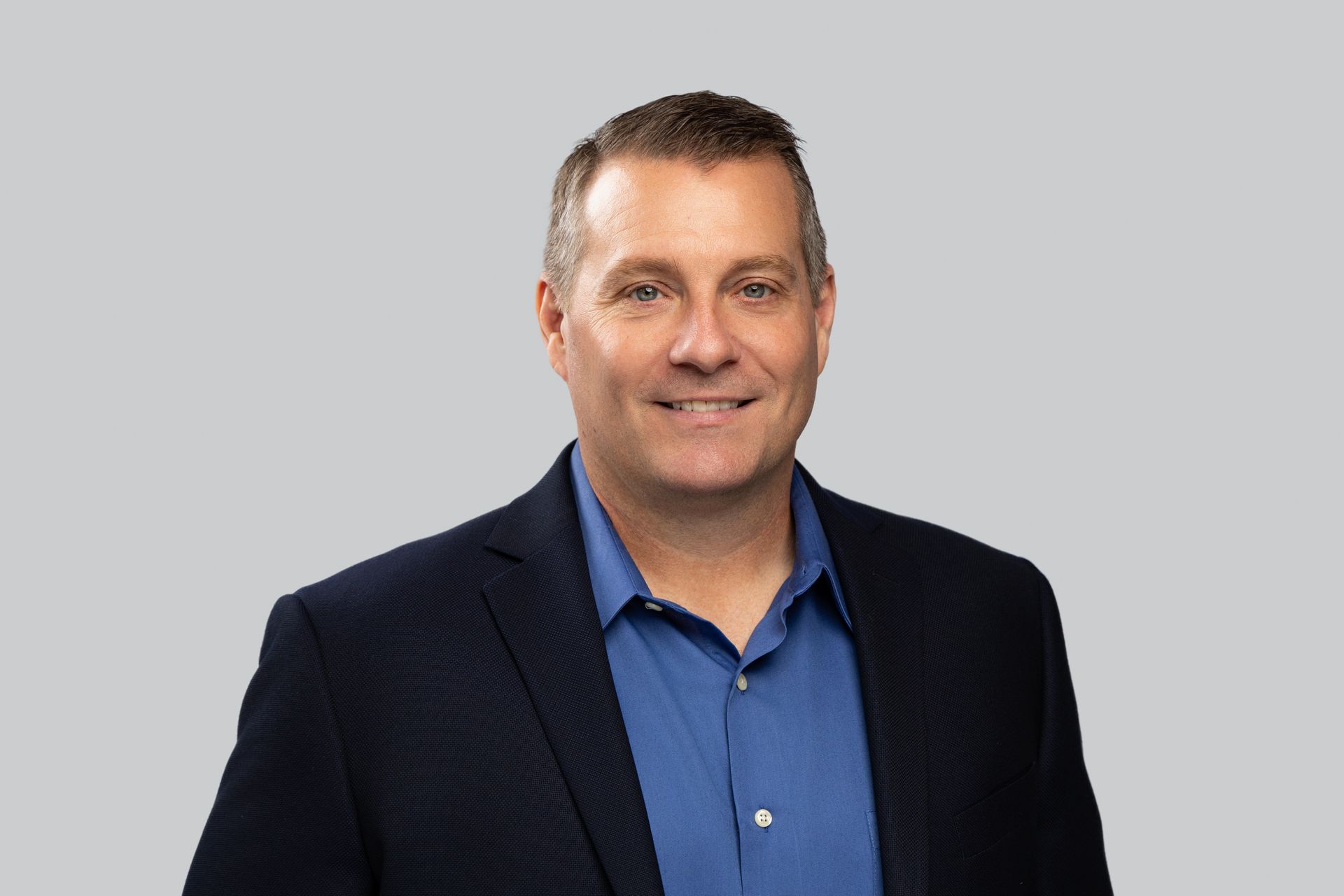 A man in a suit and blue shirt is smiling for the camera.