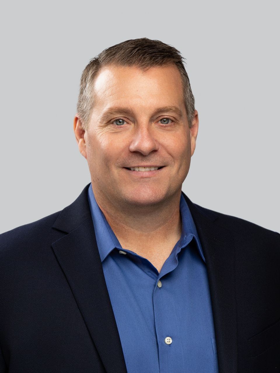 A man in a suit and blue shirt is smiling for the camera.