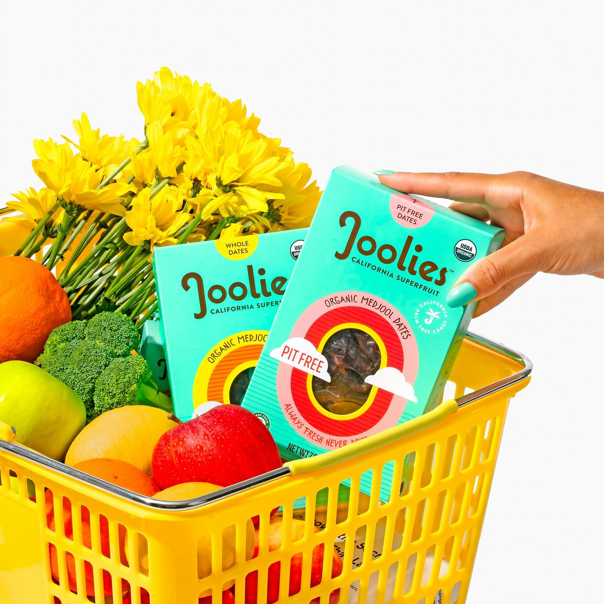 A person is holding two boxes of joolies in a yellow basket