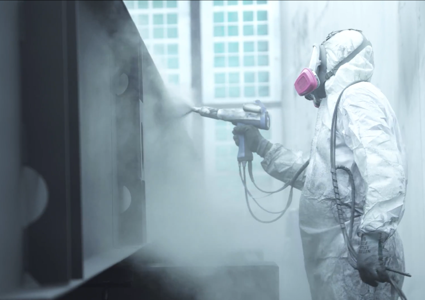 Painter applying powder coating to metal parts at United Alloy facility.