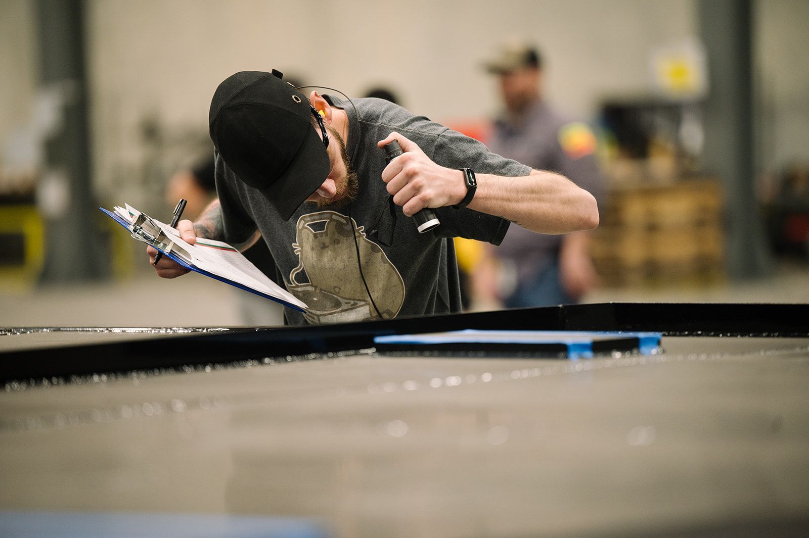 Quality Auditor inspecting a large metal frame with flashlight.