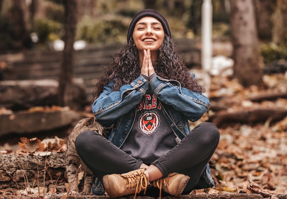 A woman is sitting in a lotus position with her legs crossed in the woods.