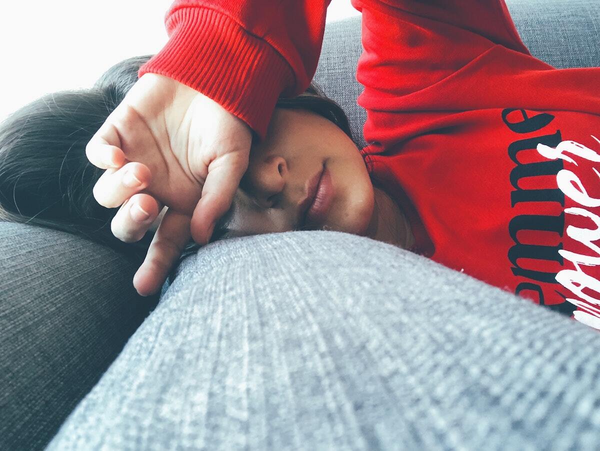 A person laying on a couch wearing a red sweater that says 