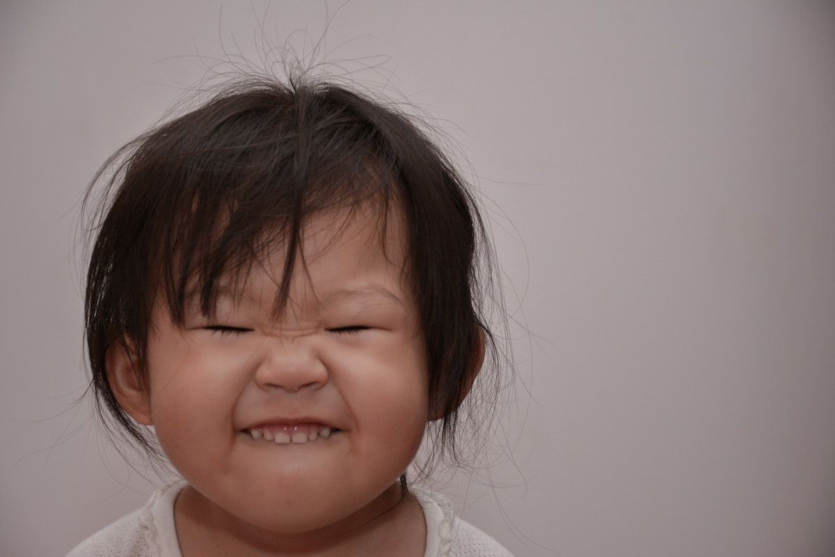 A little girl is making a funny face with her eyes closed.