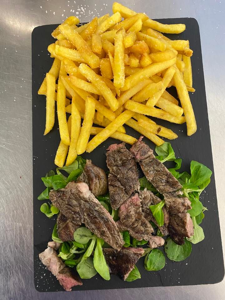 Un piatto di bistecca e patatine fritte su un tavolo.