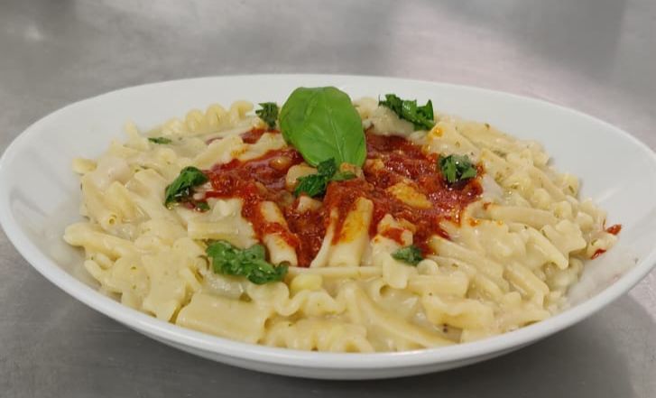 Un piatto bianco con pasta e salsa su un tavolo.