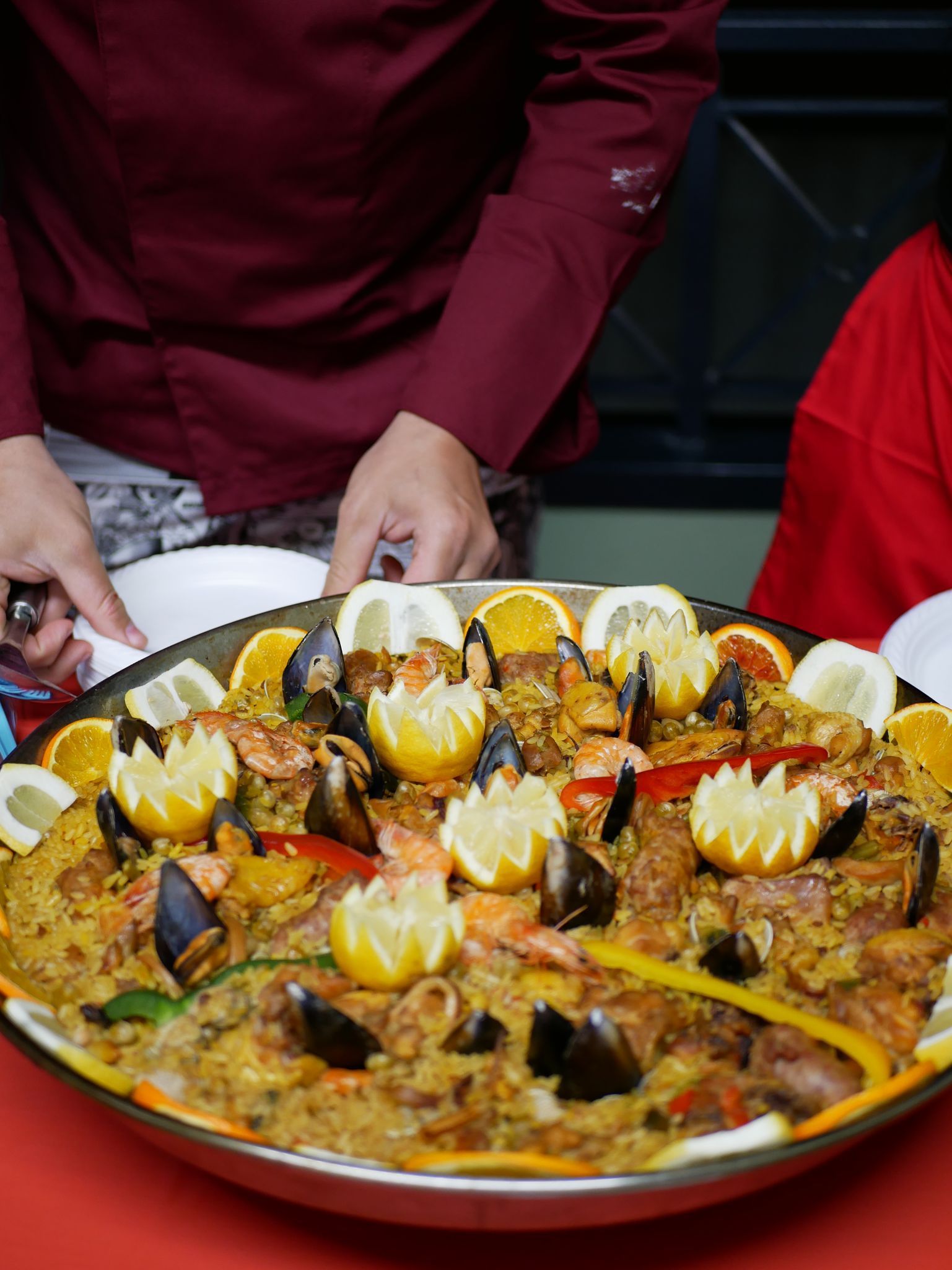 Una persona tiene in mano un piatto di cibo su un tavolo.