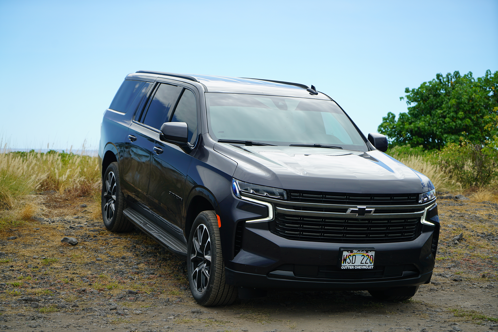 A black suv is parked in the middle of a dirt field.