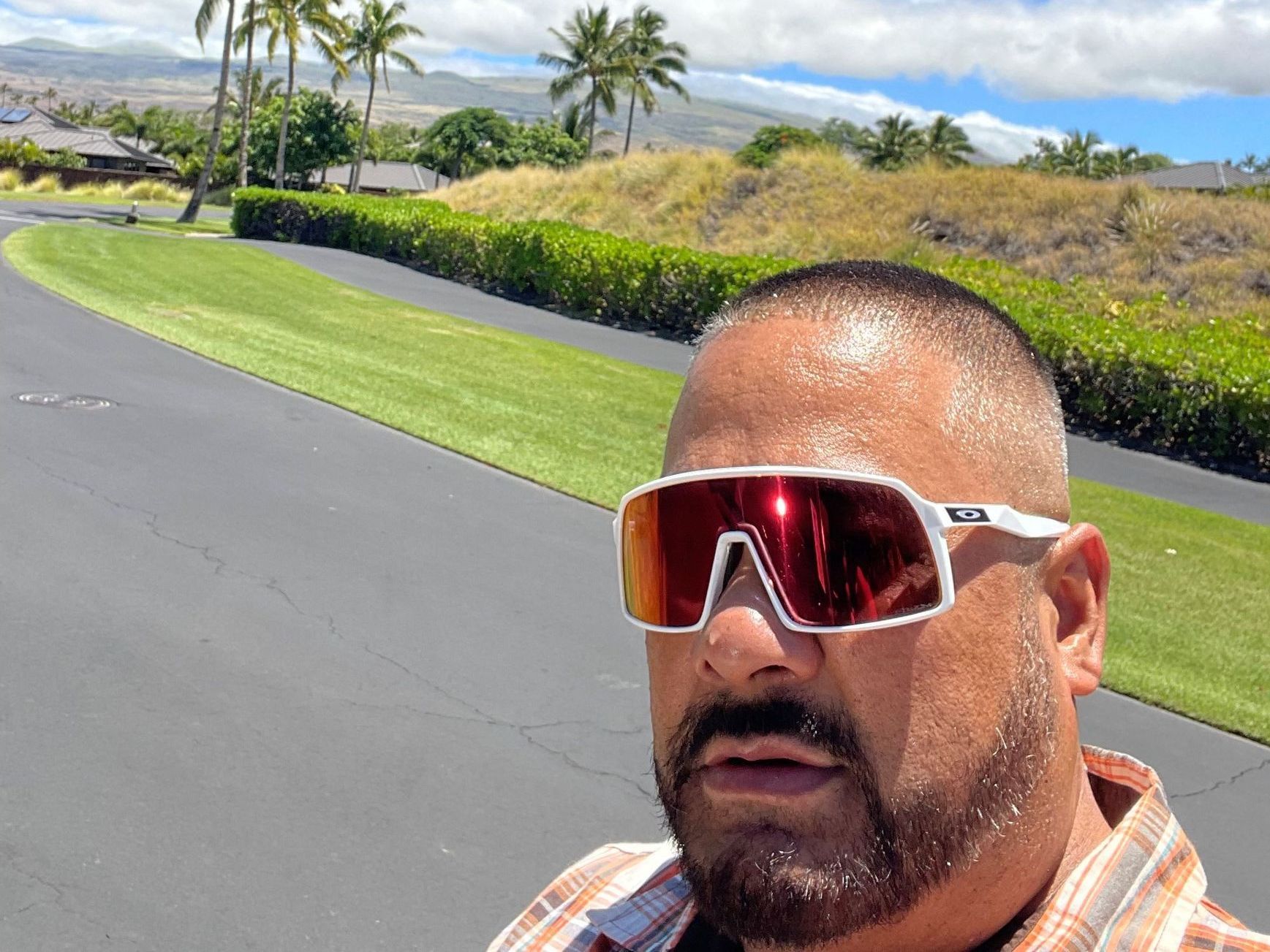 A man wearing sunglasses is standing on a road.