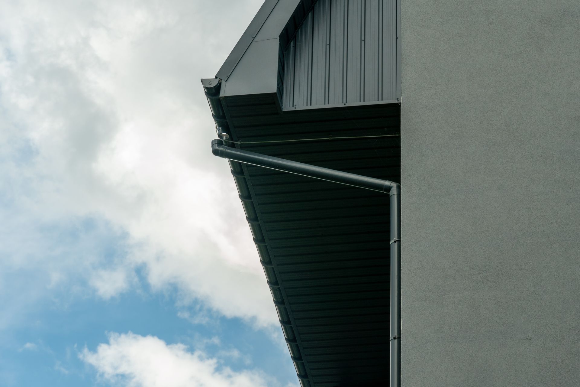 Modern building with seamless gutters and a downspout for efficient rainwater drainage