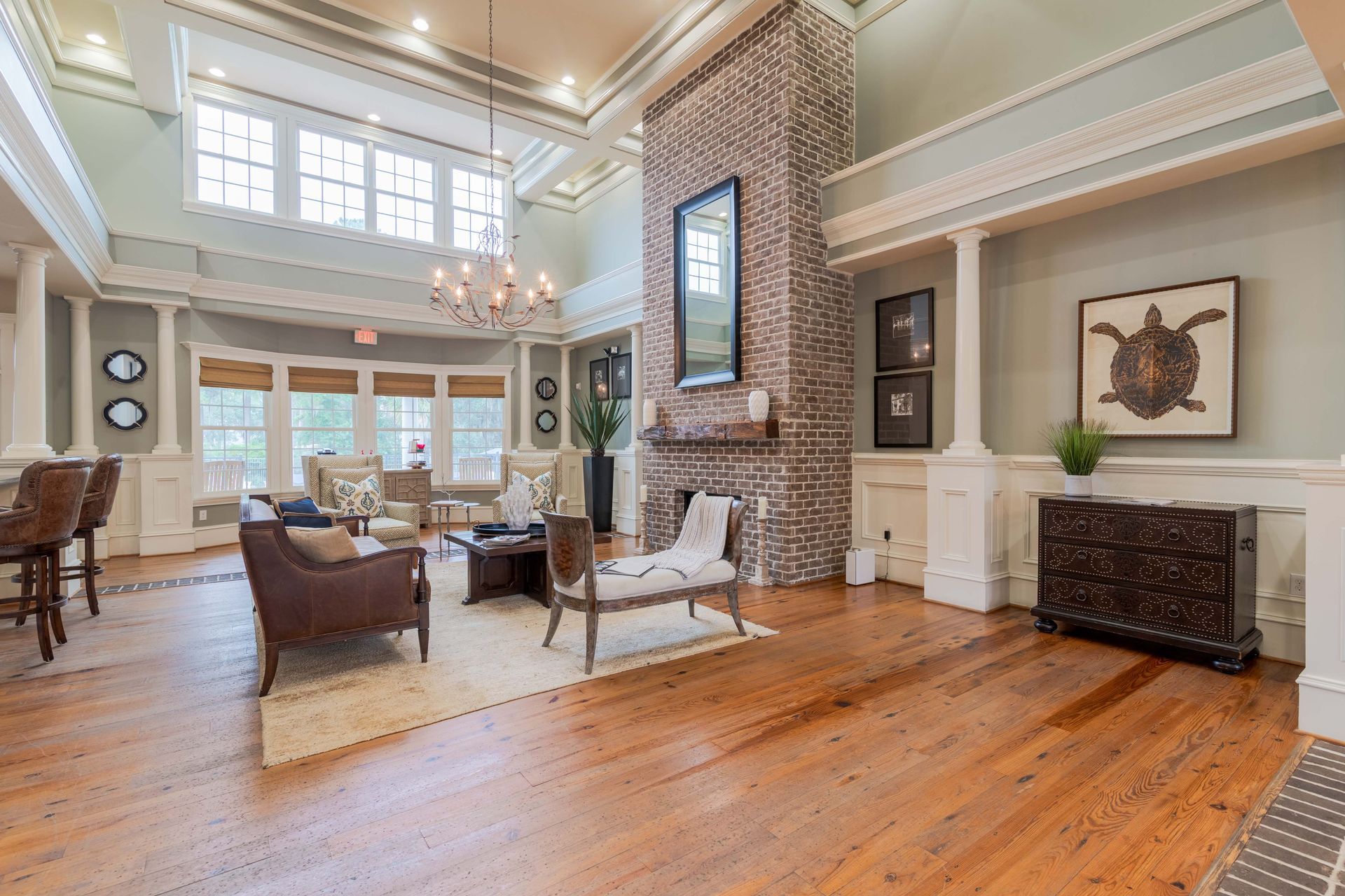 Spacious living area with wooden floor, brick fireplace, and furniture. Pastel walls and decorative molding at Grand Oaks at Ogeechee River, offers apartments for rent in Savannah, GA.