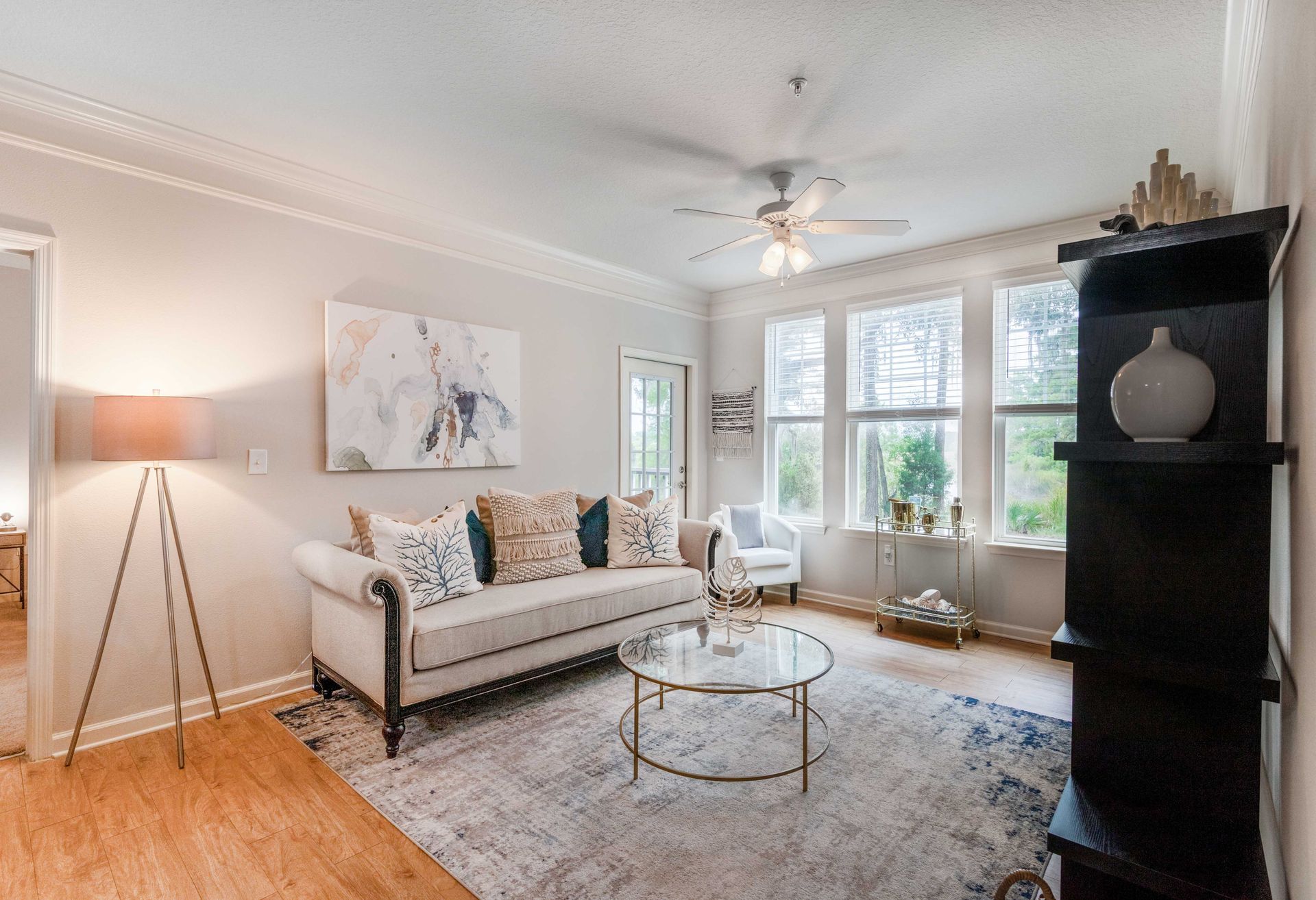 Living room with sofa, coffee table, rug, artwork, and windows at Grand Oaks at Ogeechee River, offers apartments in Savannah, GA.