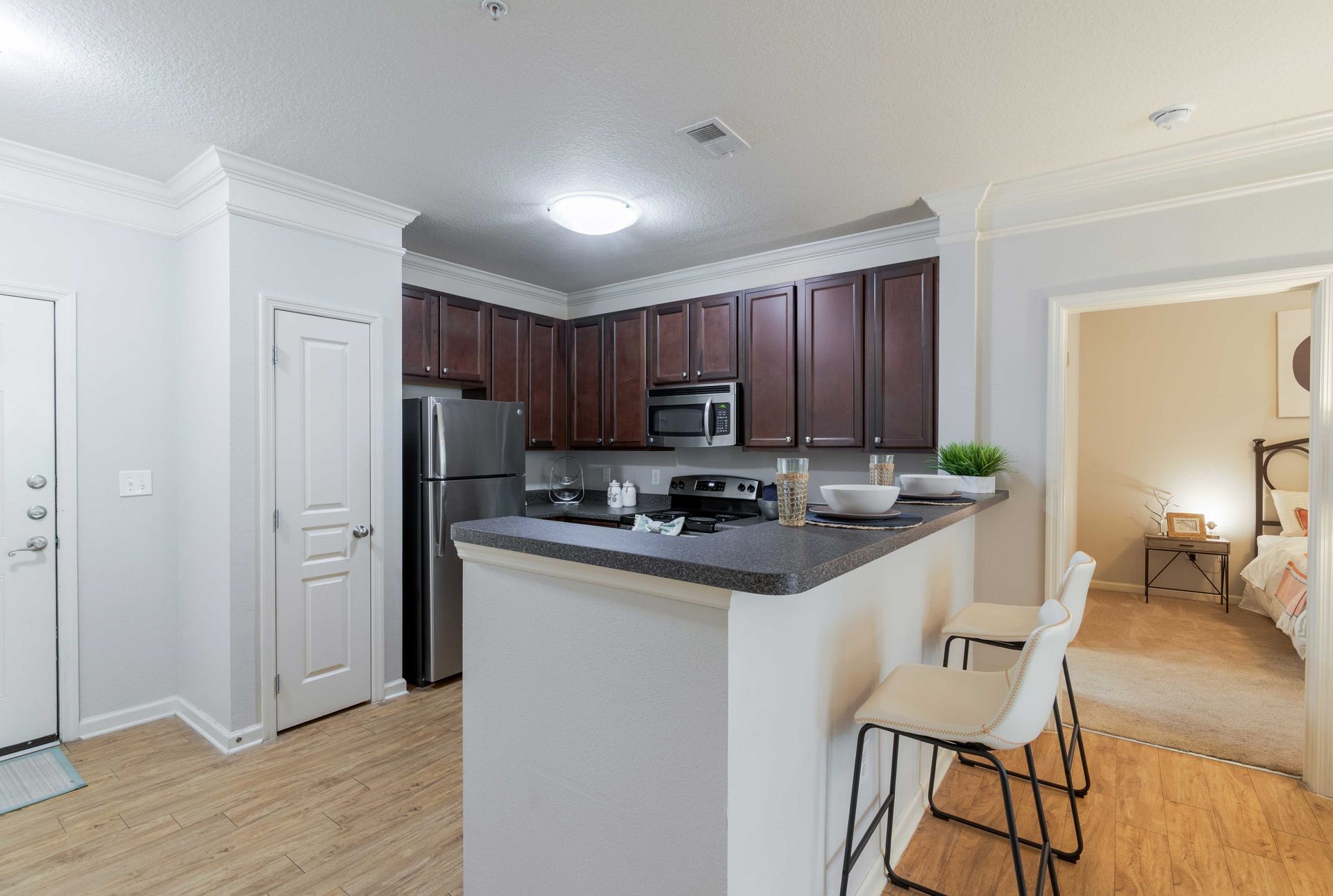 Kitchen with dark cabinets, stainless steel appliances, breakfast bar, and doorway to a bedroom at Grand Oaks at Ogeechee River, offers apartments in Savannah, GA.