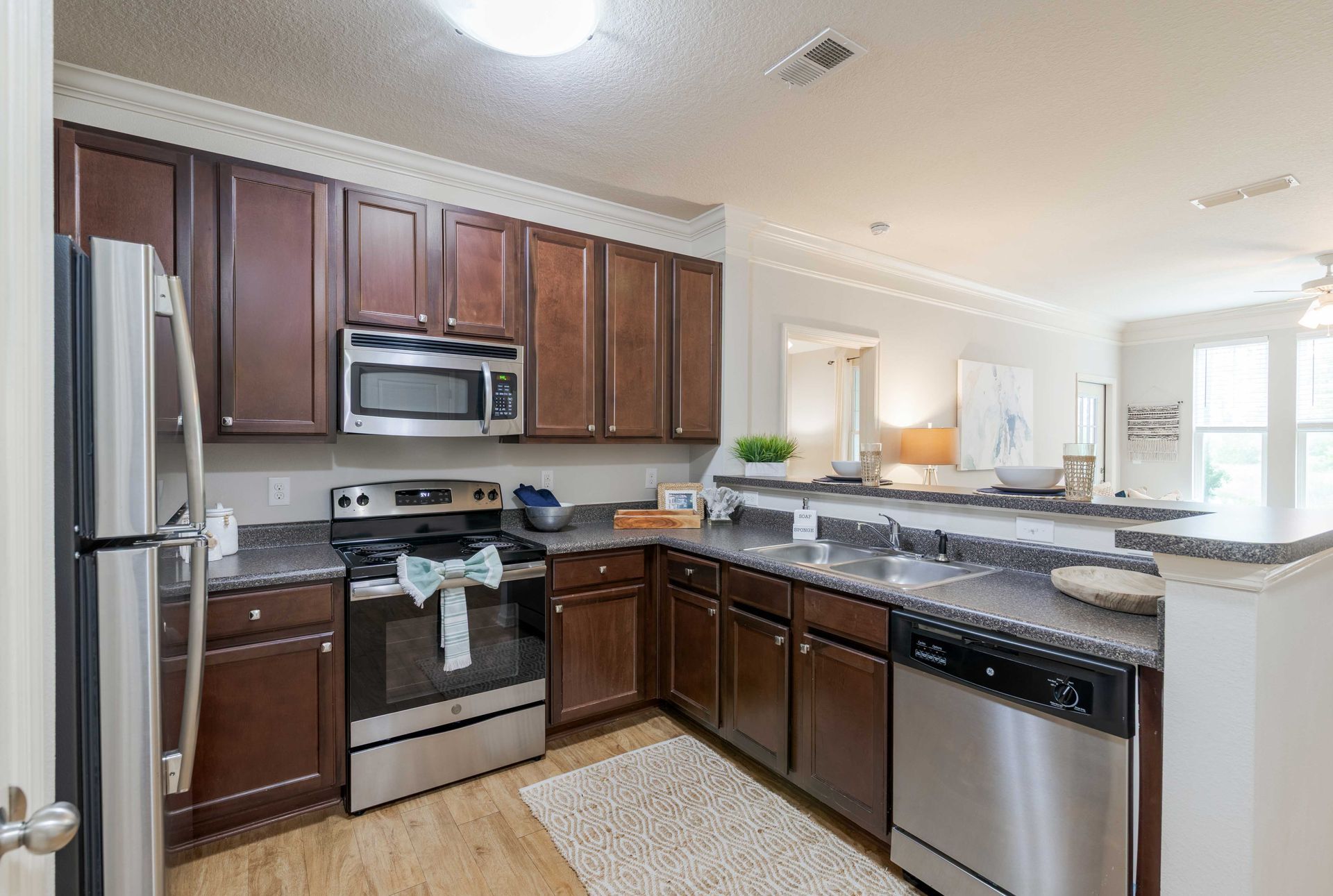 Kitchen with brown cabinets, stainless steel appliances, and gray countertops at Grand Oaks at Ogeechee River, offers apartments in Savannah, GA.