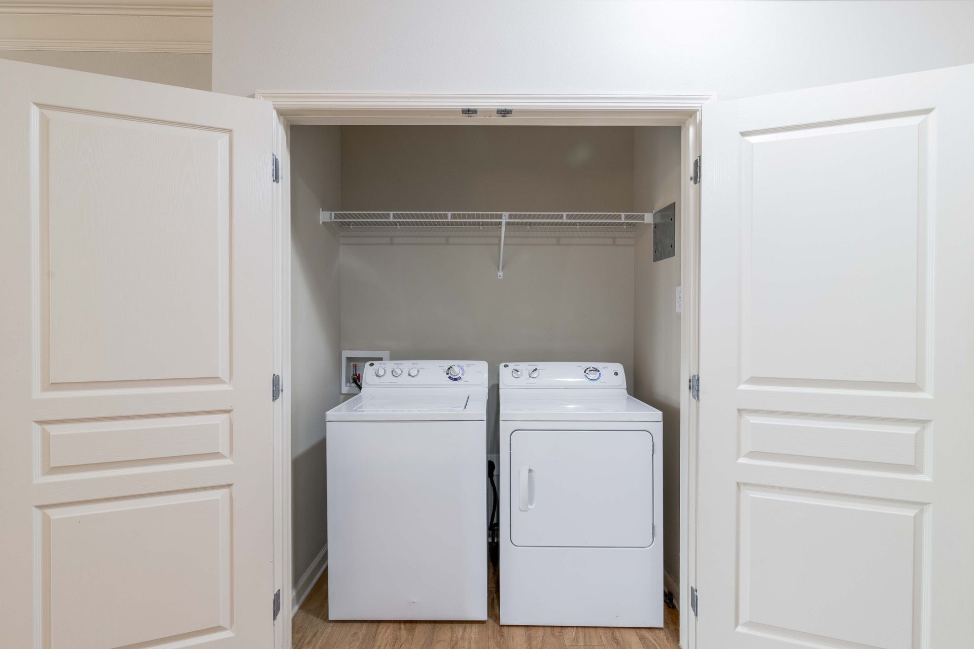 White washer and dryer in a closet with open white doors; a wire rack is above at Grand Oaks at Ogeechee River, offers apartments in Savannah, GA.