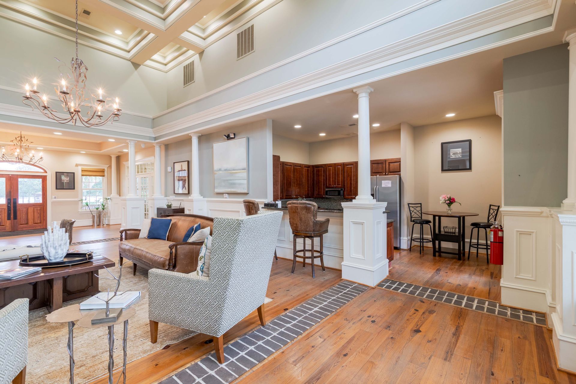 Elegant open-concept clubhouse with columns, wood floors, seating, and a small kitchen area at Grand Oaks at Ogeechee River, offers apartments for rent in Savannah, GA.