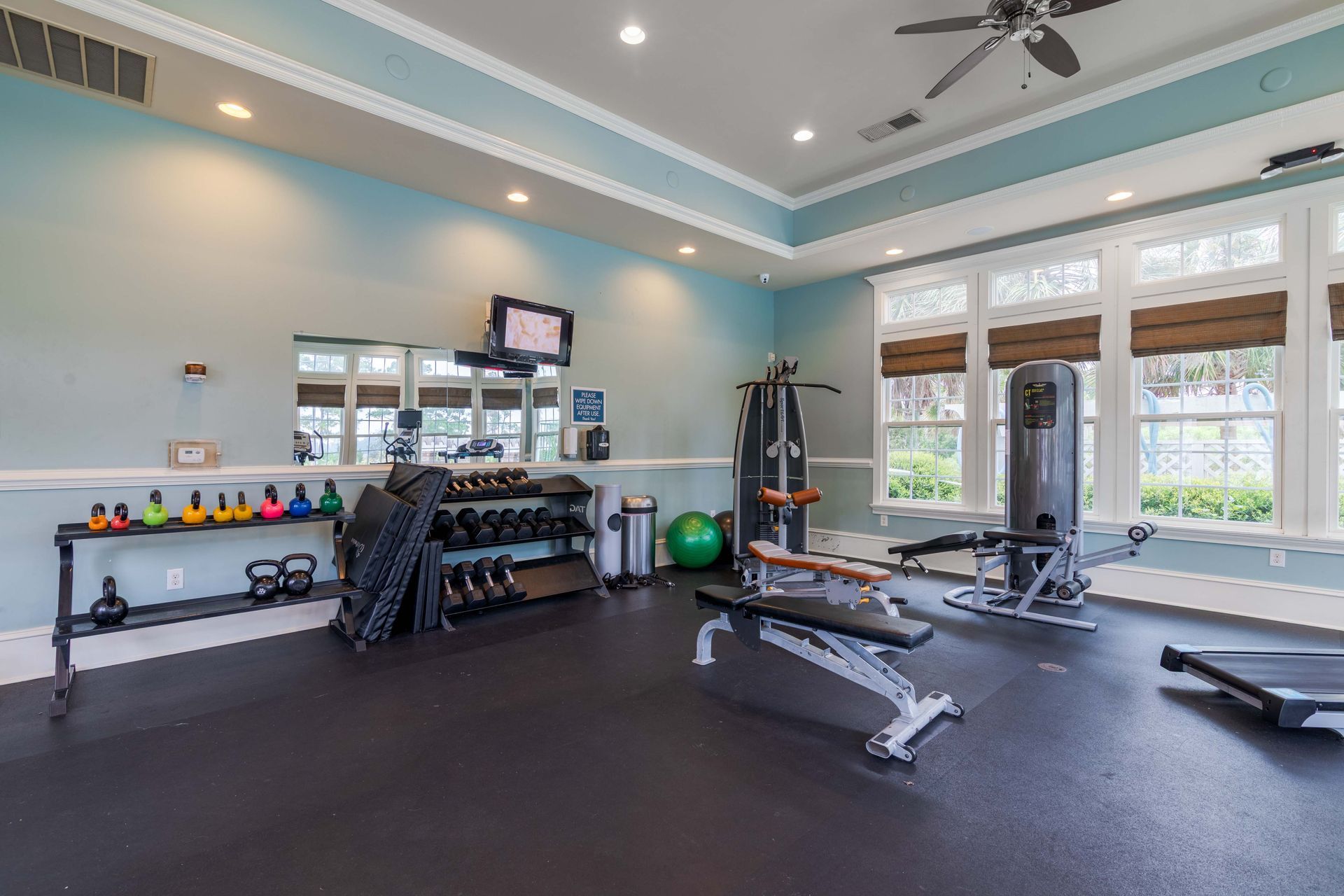 Gym with exercise equipment, including weights, a multi-gym, and a bench, with windows at Grand Oaks at Ogeechee River, offers apartments for rent in Savannah, GA.