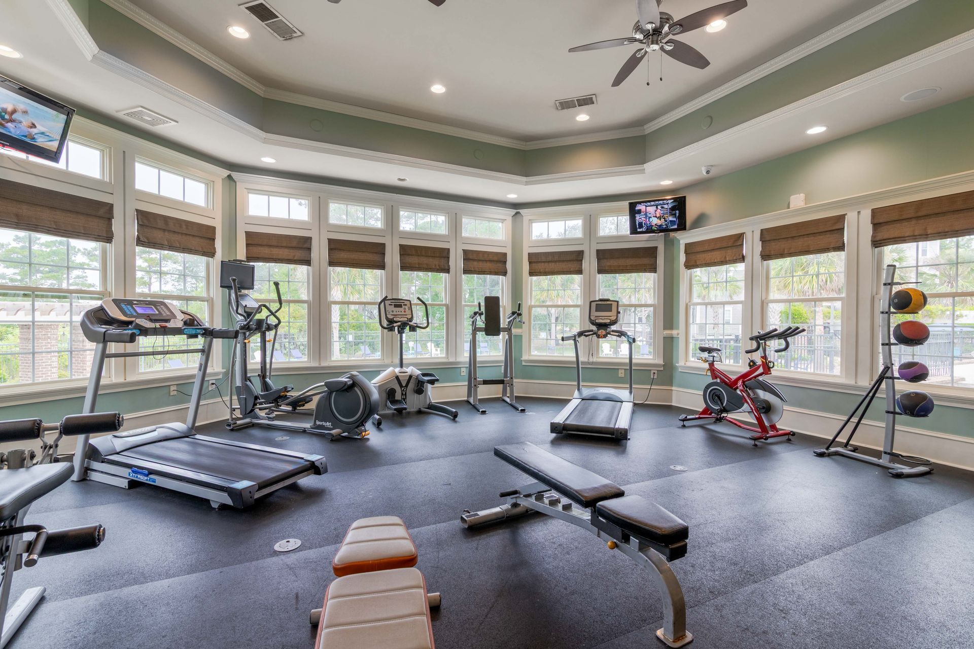 Gym with treadmills, elliptical, exercise bike, weights, and large windows at Grand Oaks at Ogeechee River, offers apartments for rent in Savannah, GA.