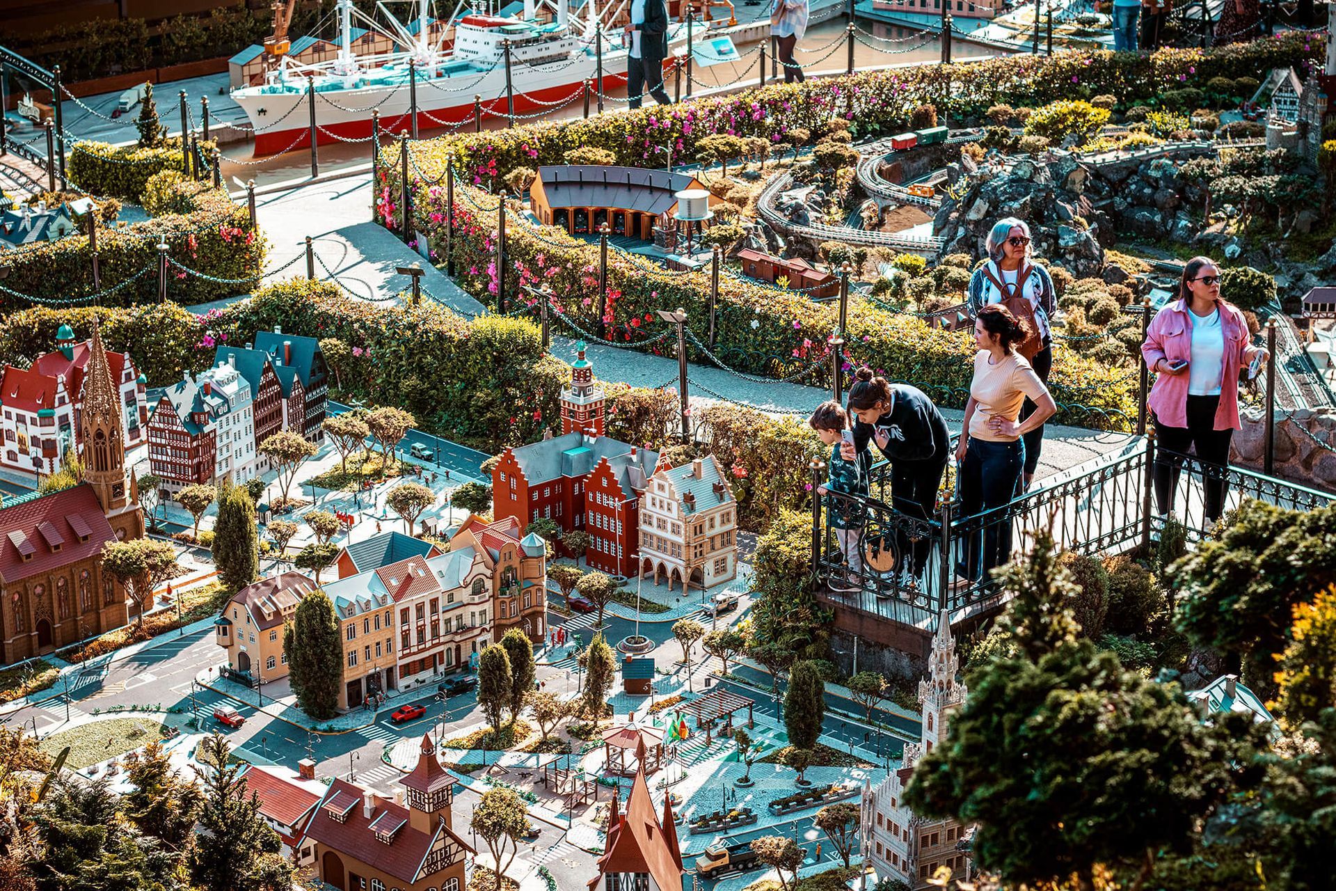 Visitantes observam as miniaturas do parque Mini Mundo, em Gramado, com construções detalhadas e jardins coloridos.