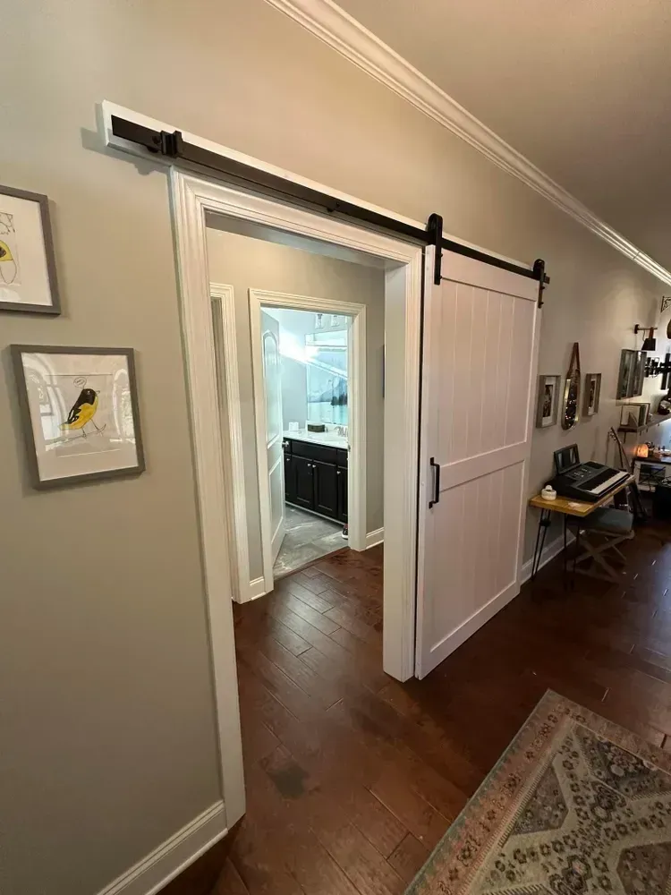 A hallway with a sliding barn door leading to a bathroom.