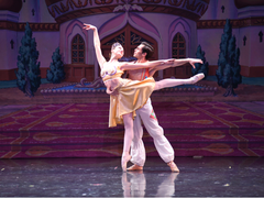 a man and a woman are dancing on a stage in front of a building that says aladdin