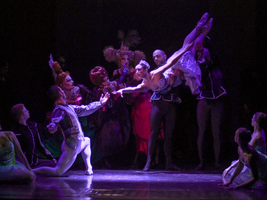 a group of people are dancing on a stage in a dark room .