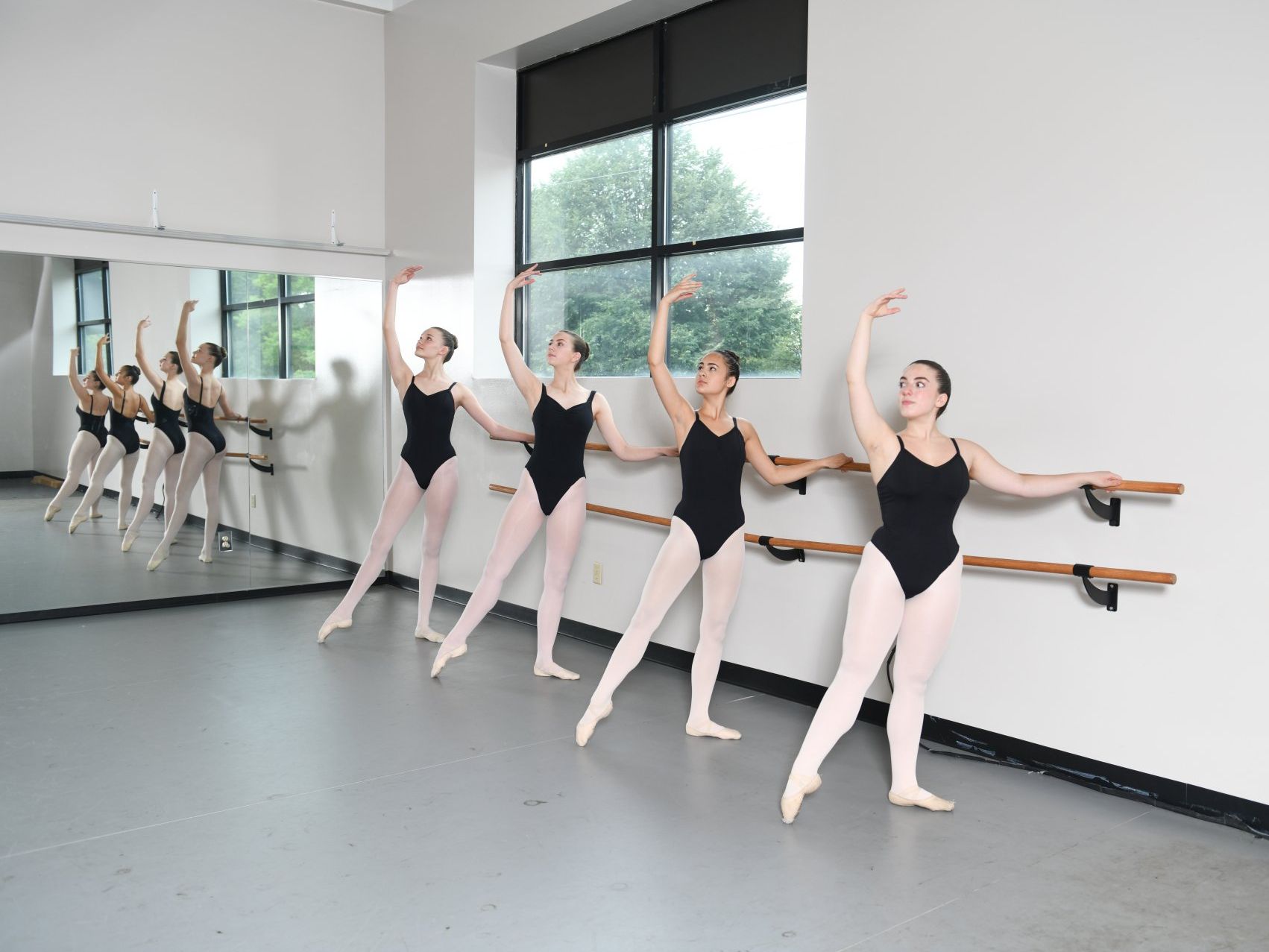 a group of young women are practicing ballet in a dance studio .