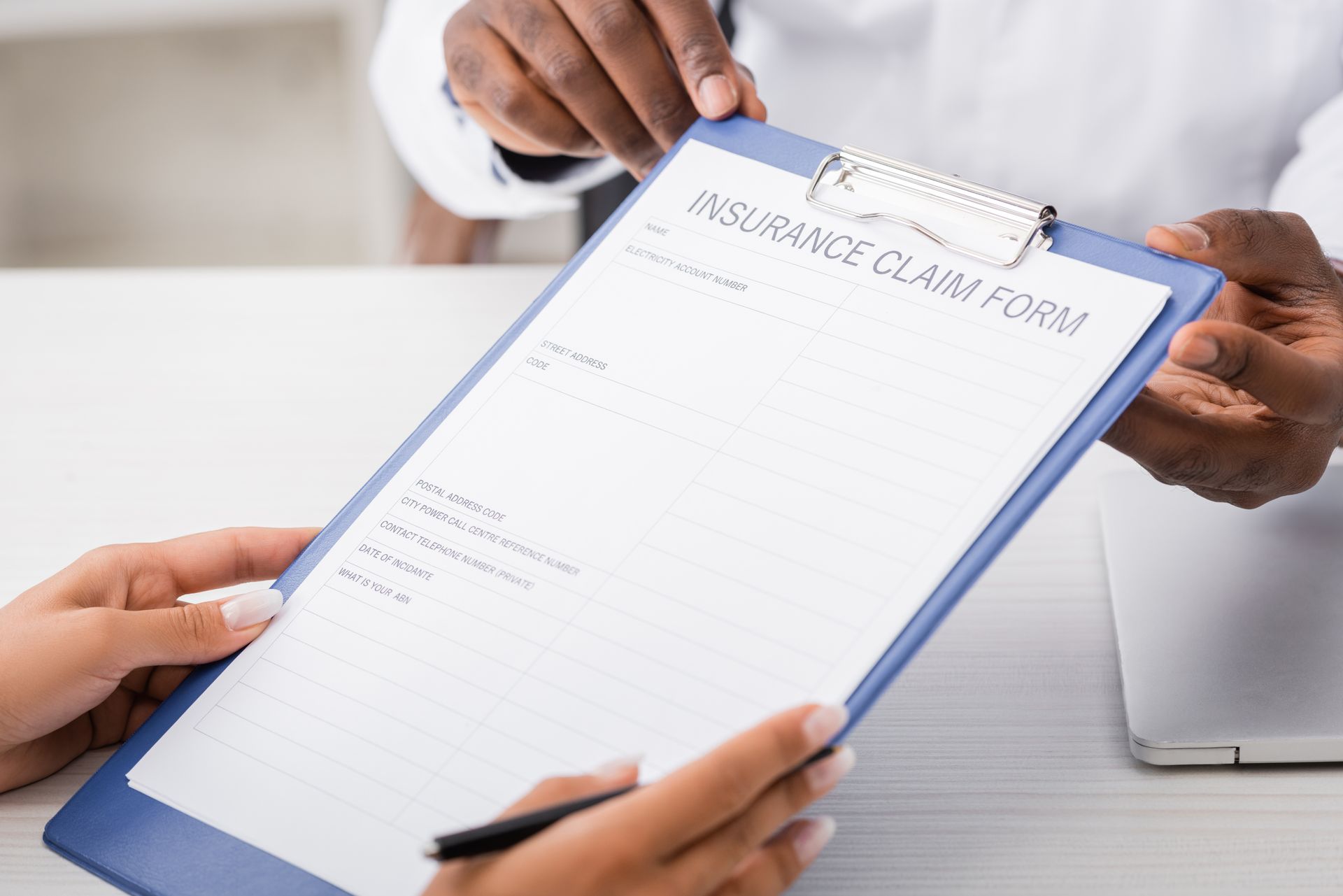 A doctor is giving a patient an insurance claim form on a clipboard.