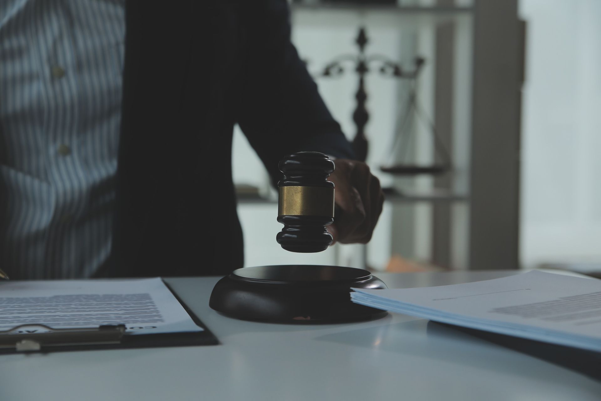 A judge is holding a gavel in his hand while sitting at a table.