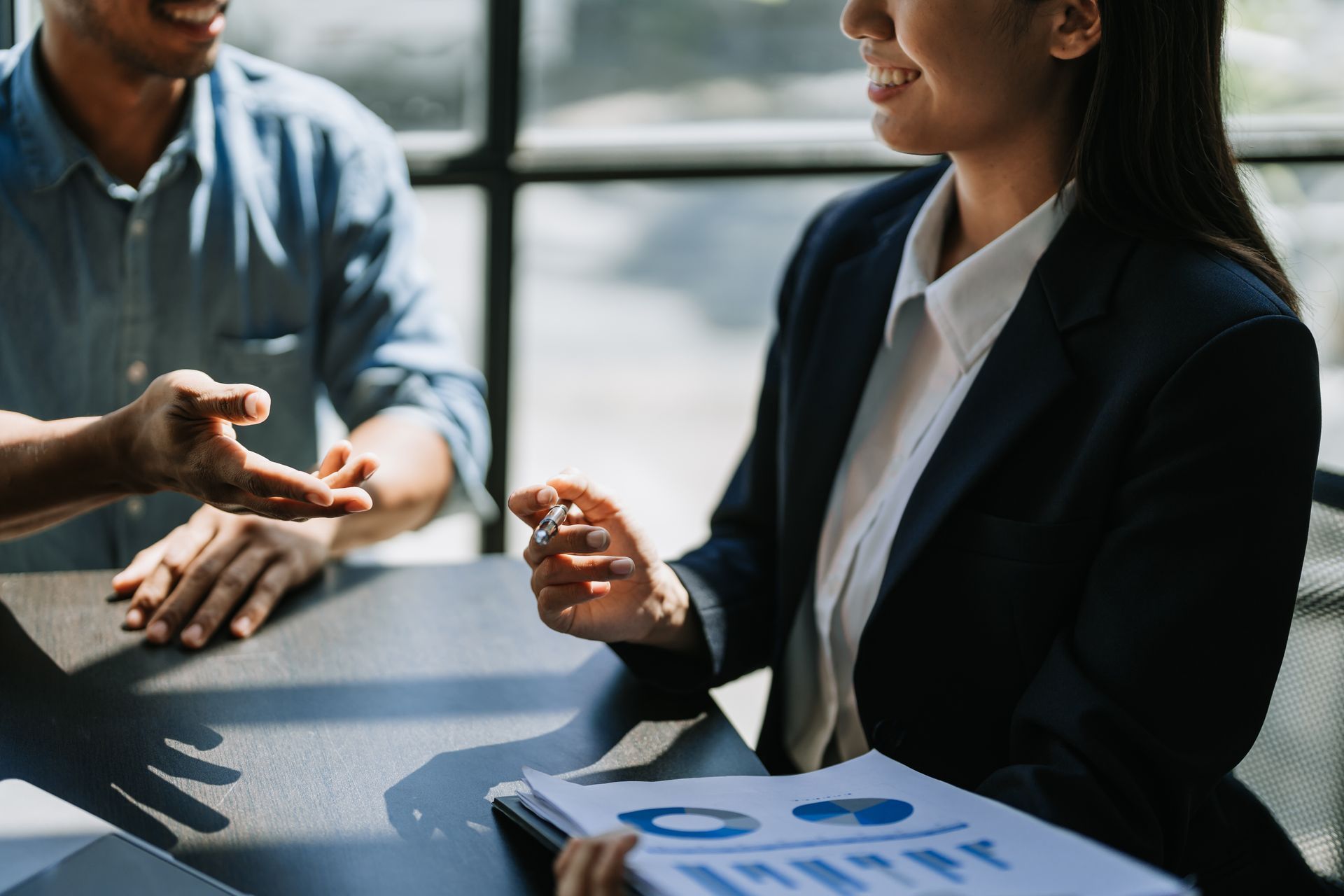 A man and a woman are sitting at a table talking to each other.