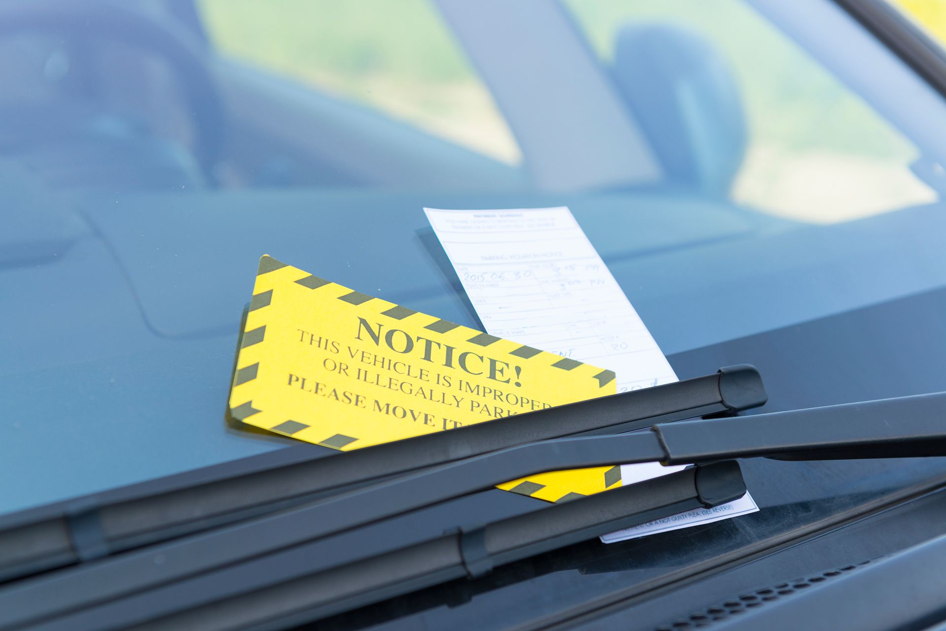 A parking ticket is on the windshield of a car.