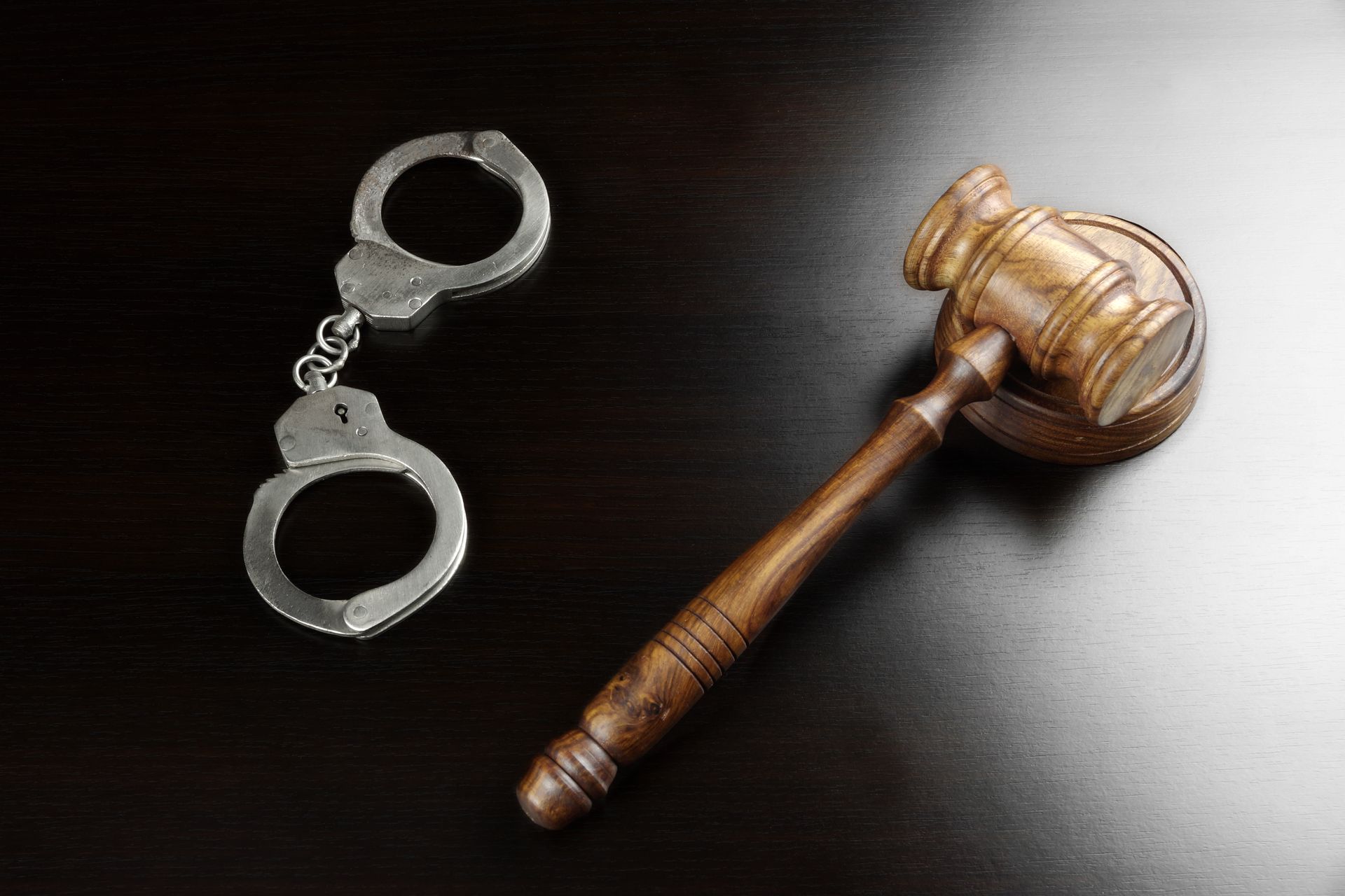 A pair of handcuffs and a judge's gavel on a table.