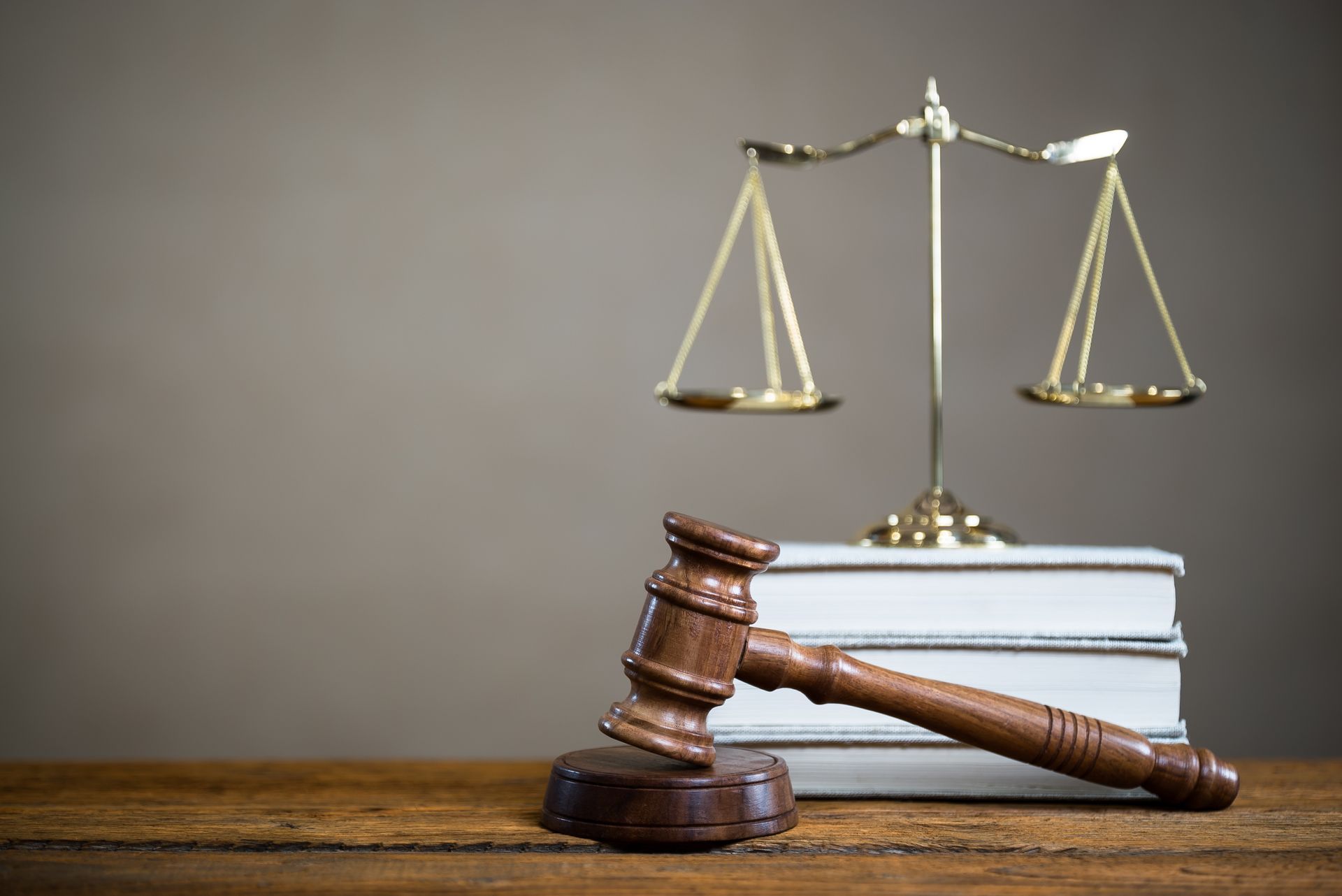 A judge's gavel and scales of justice are on a wooden table.