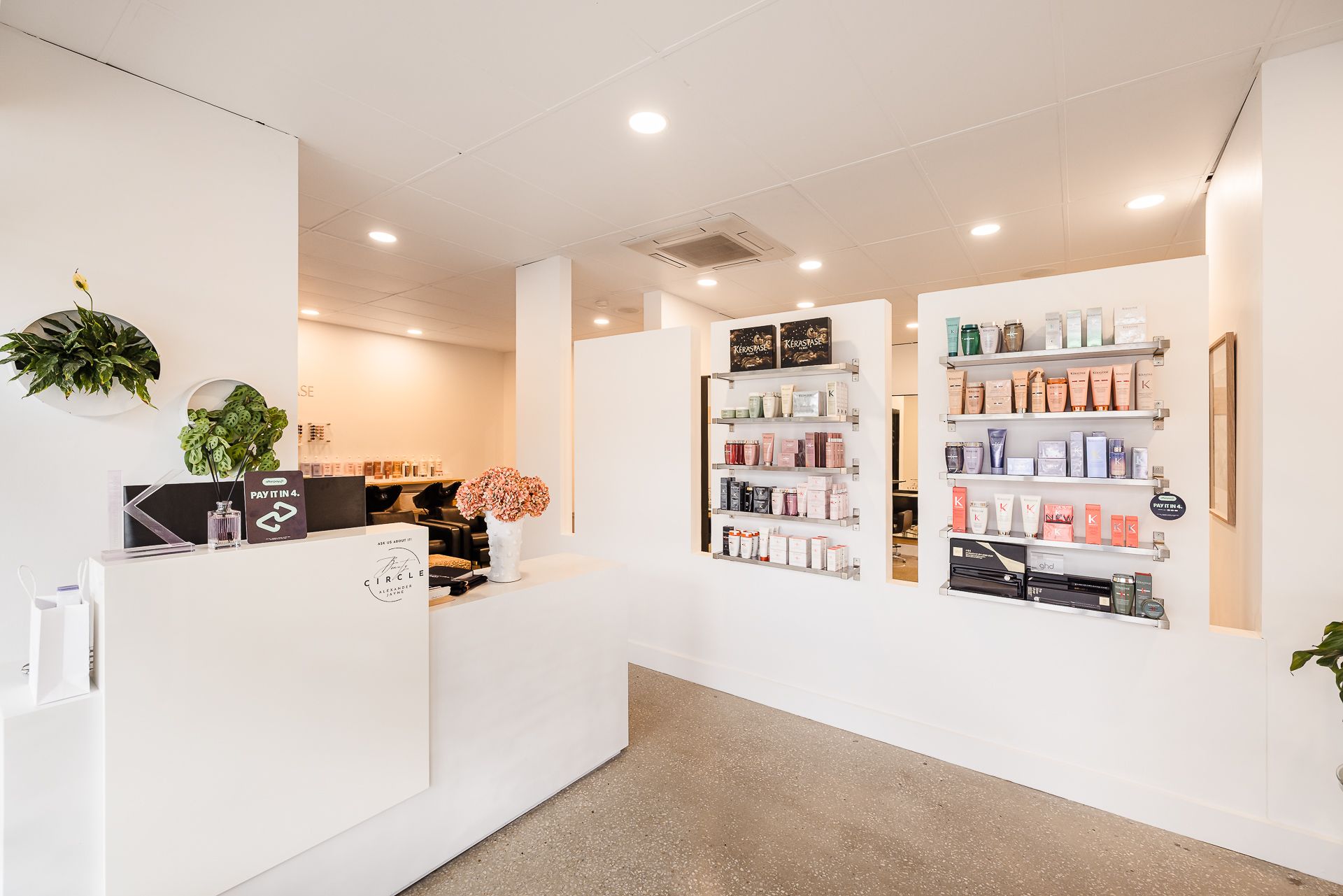 A salon with a reception desk and shelves filled with hair products.