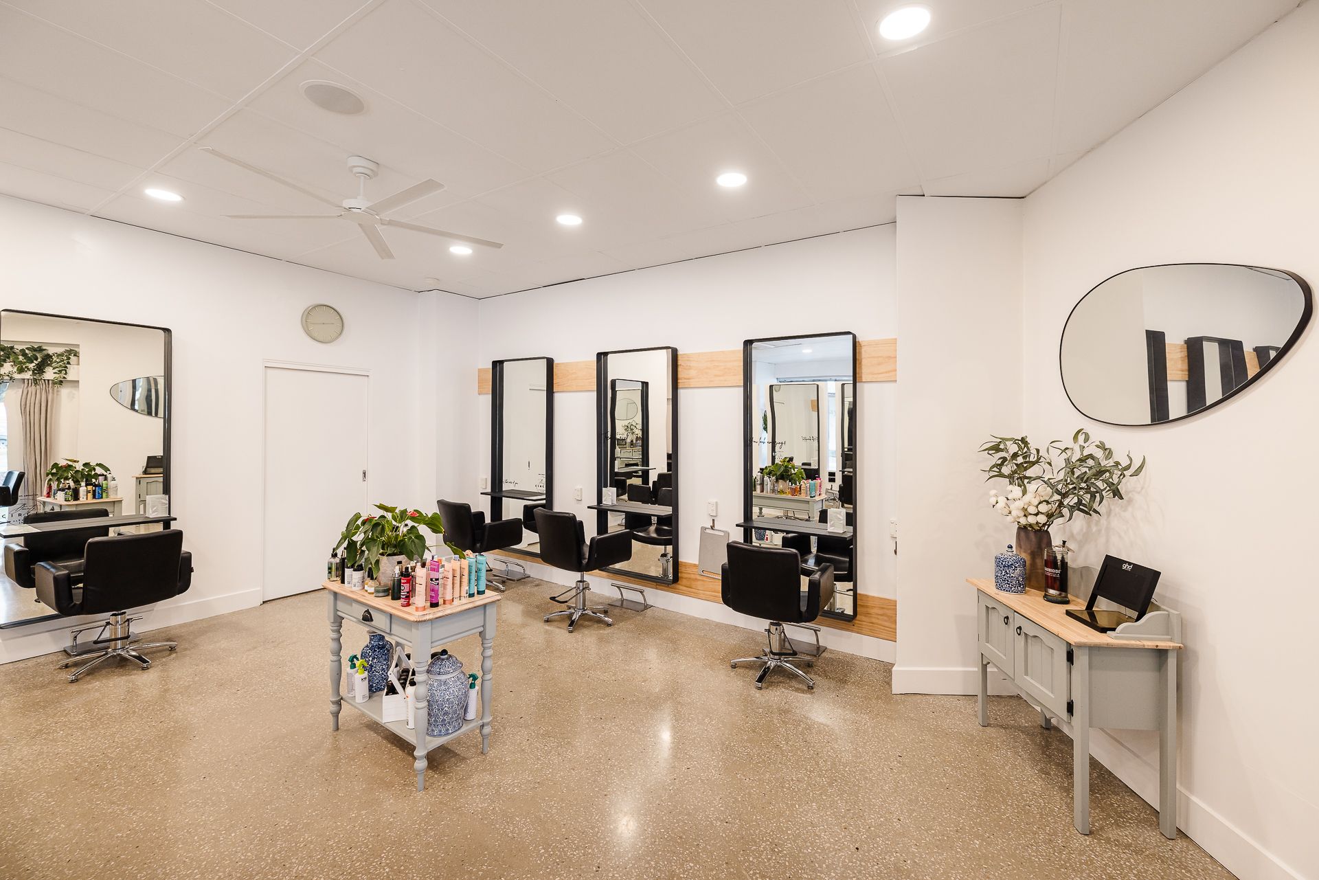 A large room with a lot of chairs and mirrors in a hair salon.