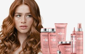 A woman with red hair is standing next to a bunch of hair products.