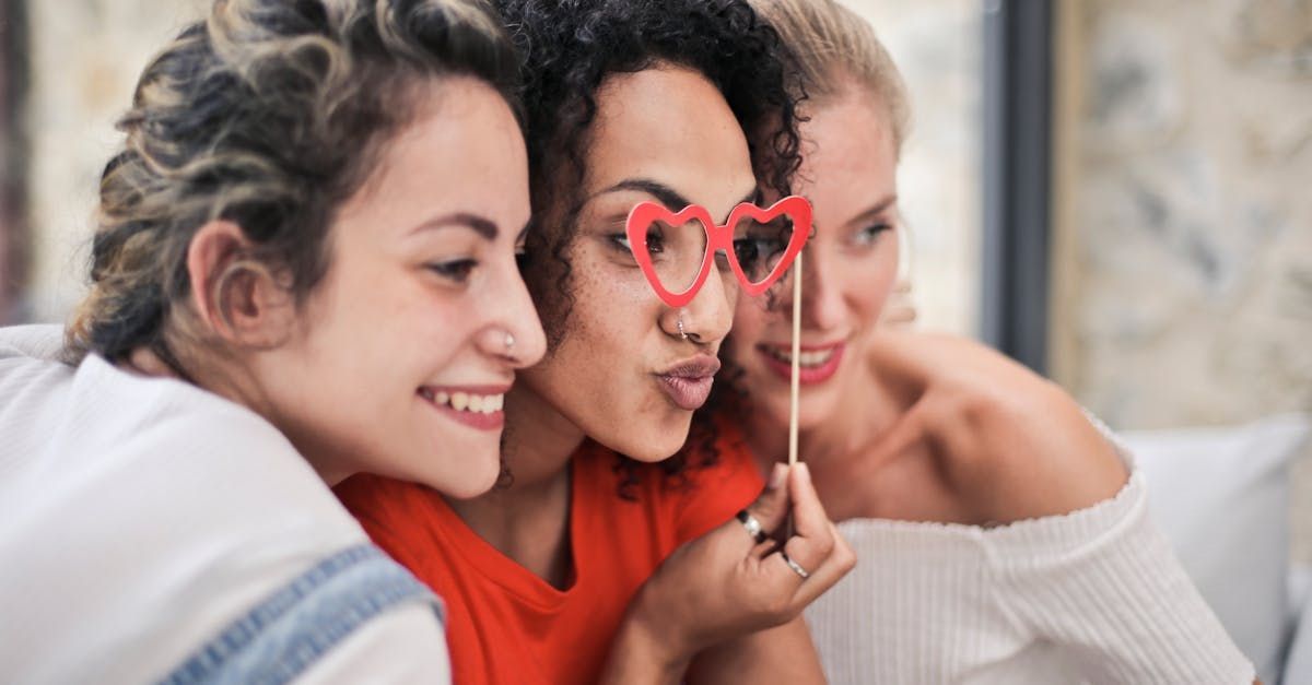 Three women are taking a selfie with heart shaped glasses.