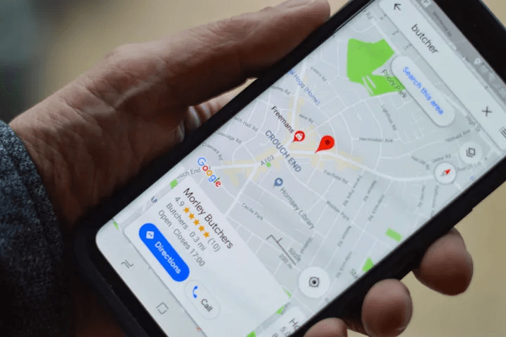 Image of a person holding a mobile phone and looking for directions on Google Maps