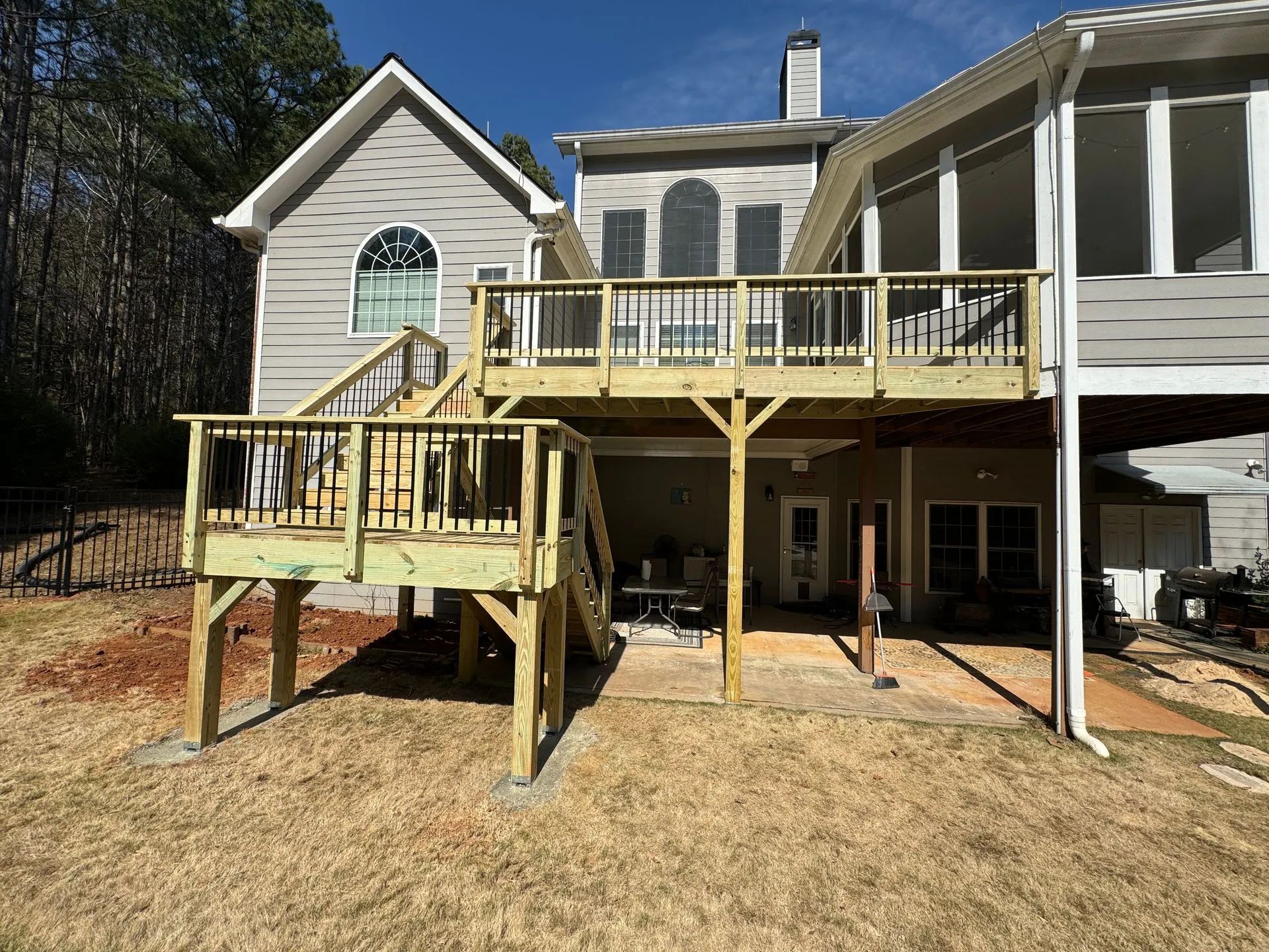 A large wooden deck is sitting in front of a house.