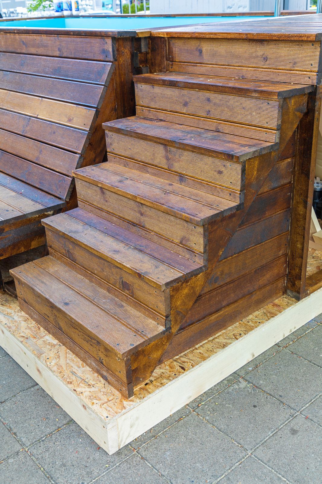 A set of wooden stairs leading up to a swimming pool.