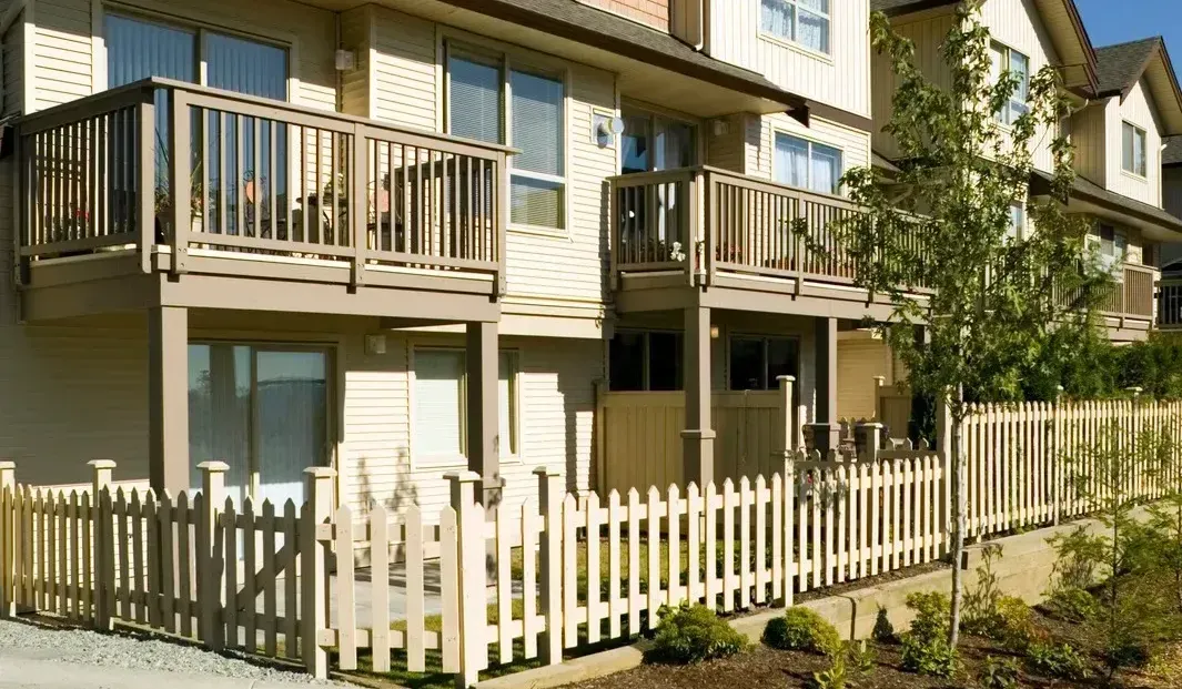 A row of houses with balconies and a picket fence