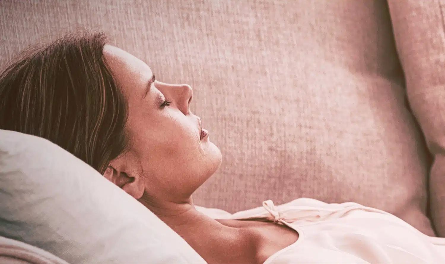 a woman peacefully laying on a couch with eyes closed.