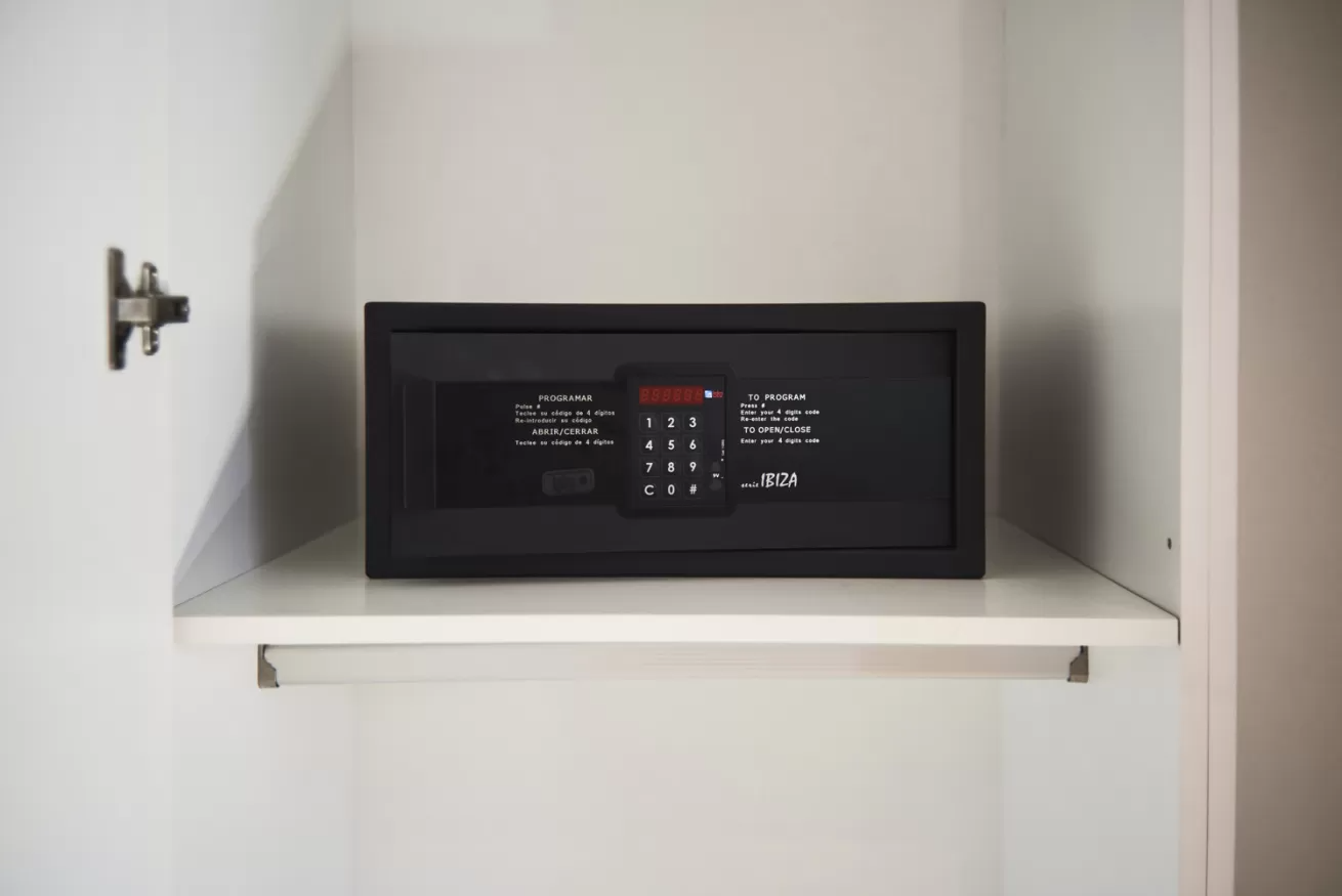 Caja fuerte negra de pared sobre un estante blanco de armario con teclado digital y pantalla