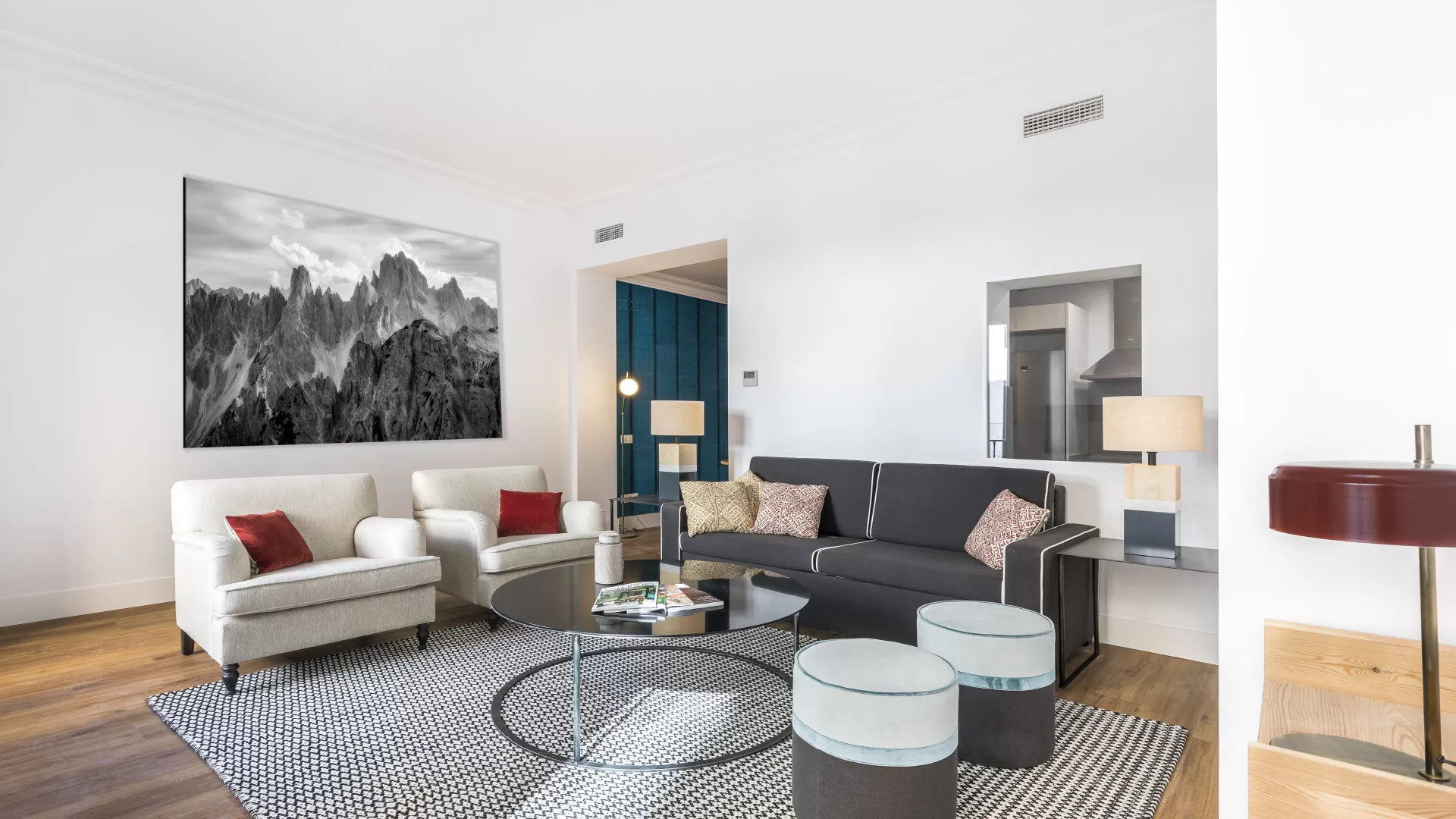 Sala de estar moderna con sofá blanco, alfombra estampada, arte en la pared y pared decorativa de color verde azulado.