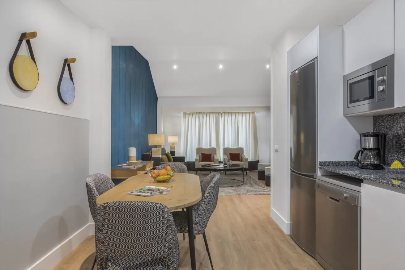 Cocina y comedor de apartamento moderno con electrodomésticos de acero inoxidable y vistas al salón.