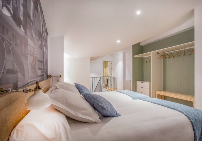 Dormitorio moderno y luminoso con una cama bien hecha, lámpara de noche y armario abierto.