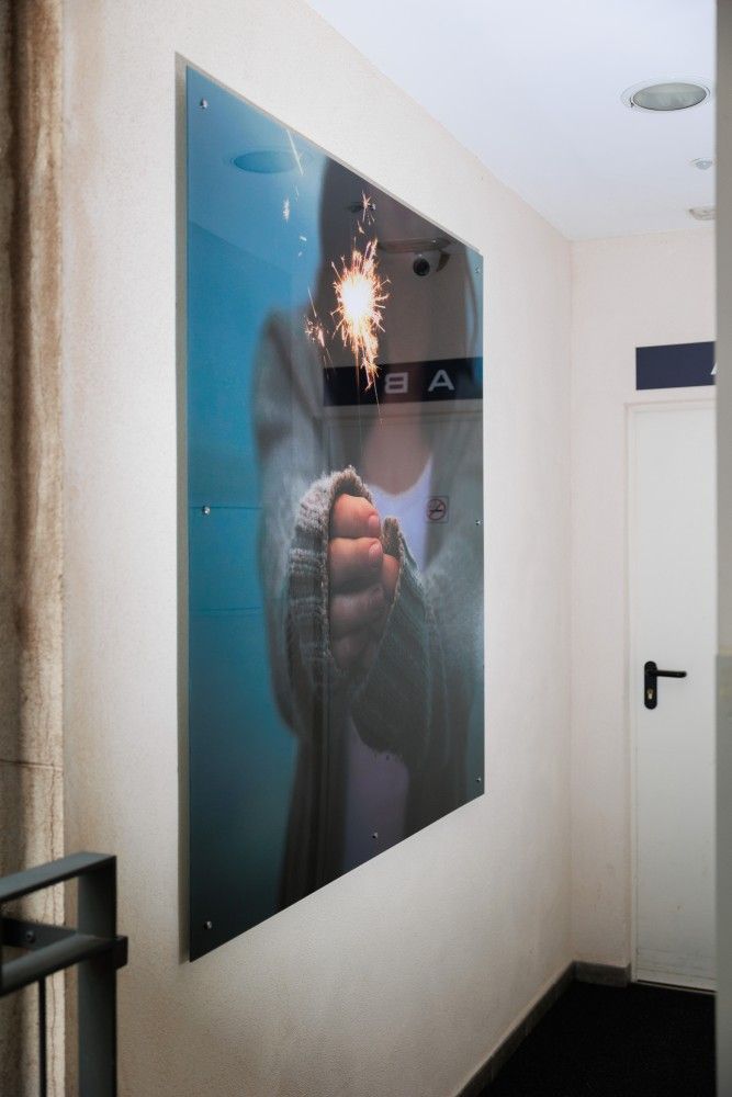 Un gran póster brillante en la pared de un pasillo muestra una mano sosteniendo una bengala encendida.